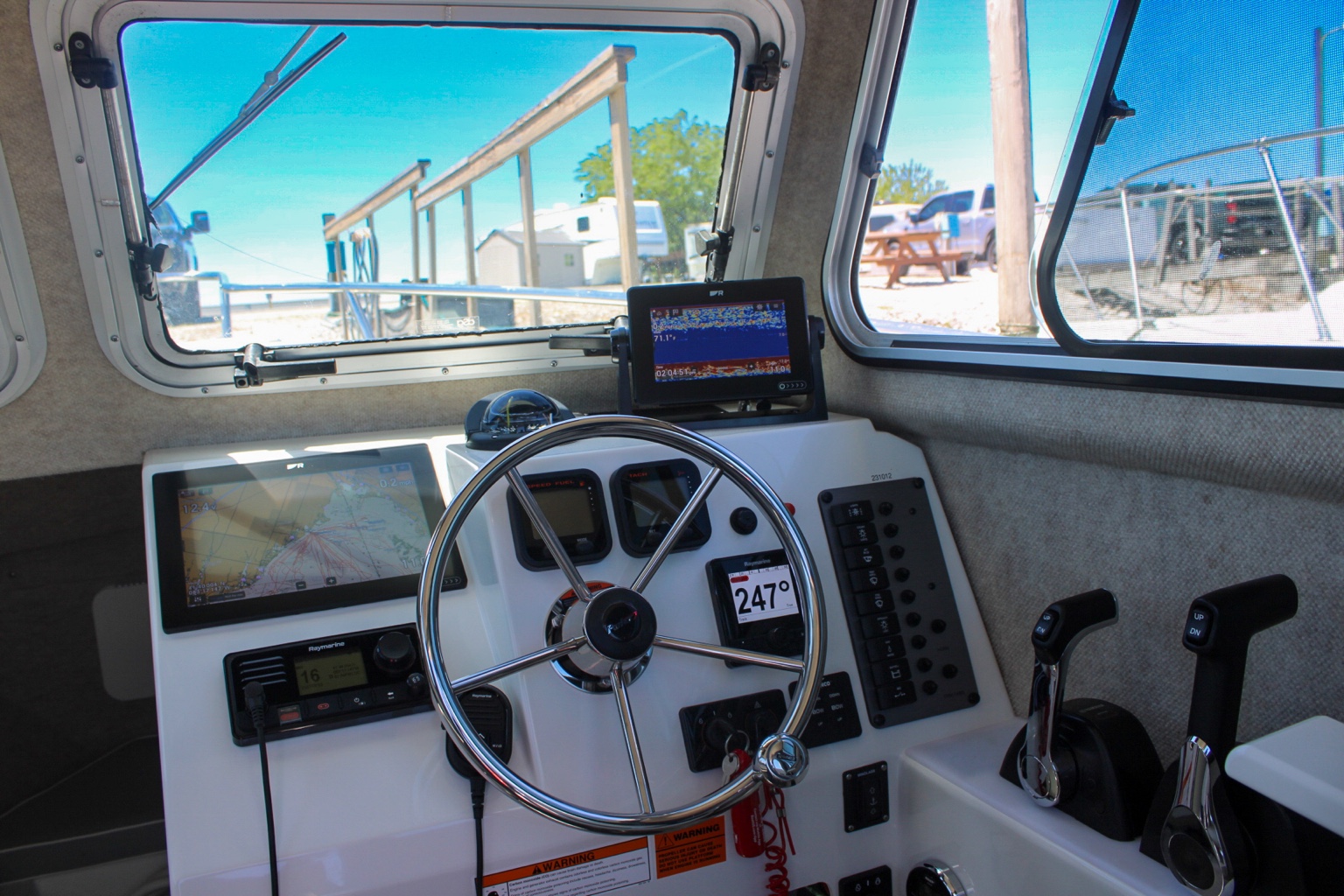 Parker pilothouse helm with Raymarine displays, steering wheel and engine controls